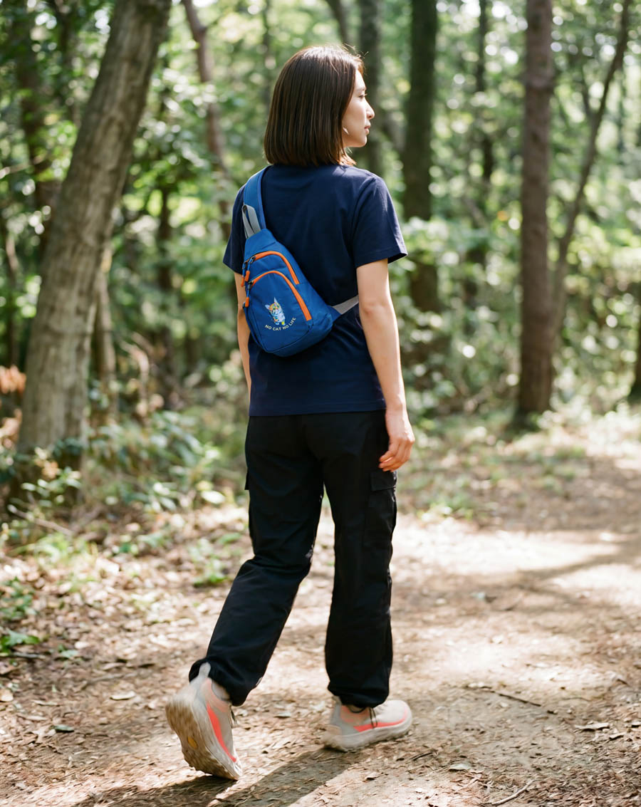 森の中を散歩する女性・ロイヤルブルーのNEKONI SLINGバッグ