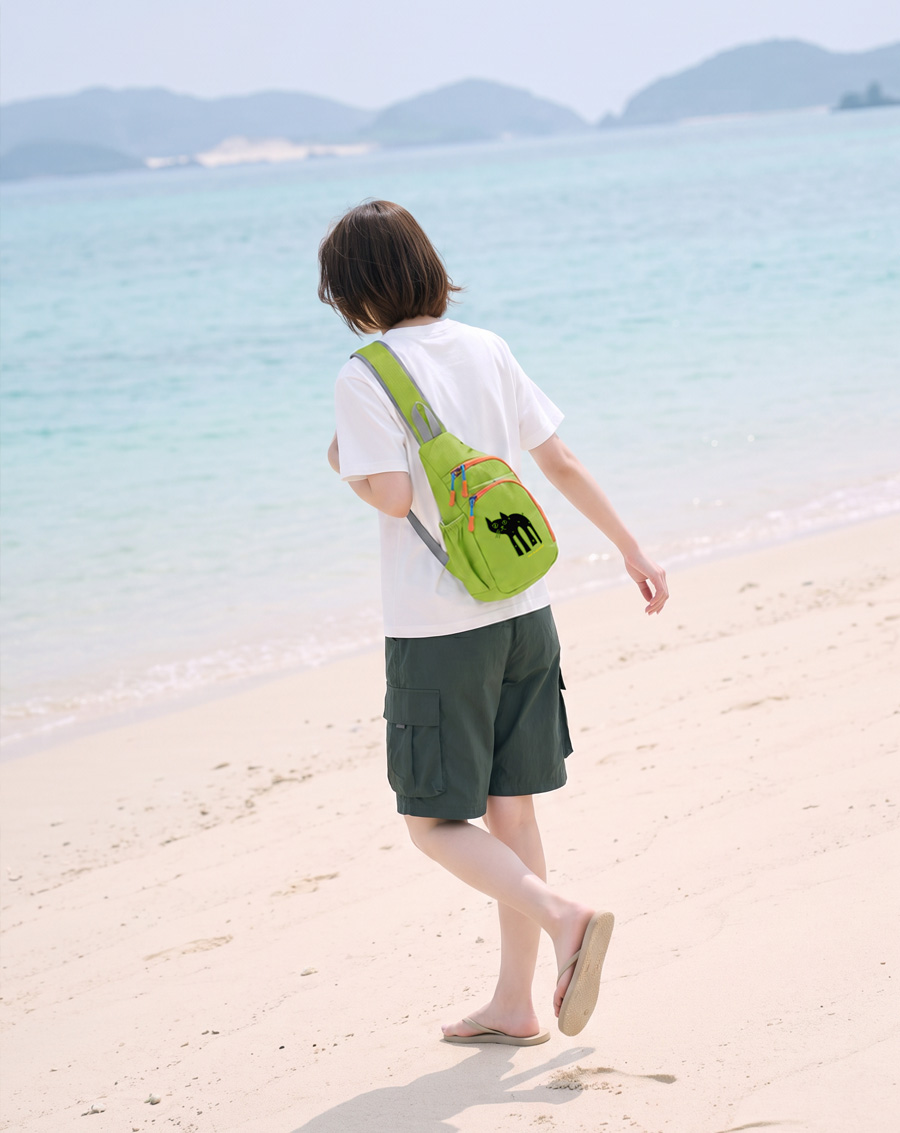 夏のビーチを歩く女性・ライトグリーンのNEKONI SLINGバッグ